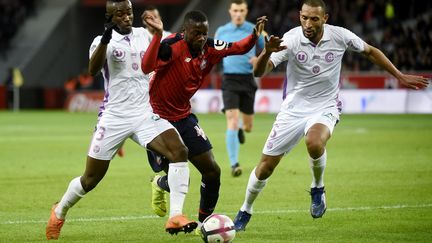 Nicolas Pépé (Lille) pris dans la tenaille rémoise (FRANCOIS LO PRESTI / AFP)