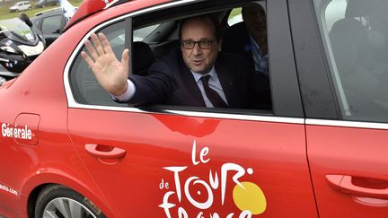 Le pr&eacute;sident fran&ccedil;ais Fran&ccedil;ois Hollande salue la foule depuis une voiture officielle du Tour de France lors de la sixi&egrave;me &eacute;tape de la course entre Arras (Pas-de-Calais), et Reims (Marne), le 10 juillet 2014. (JEFF PACHOUD / AFP)