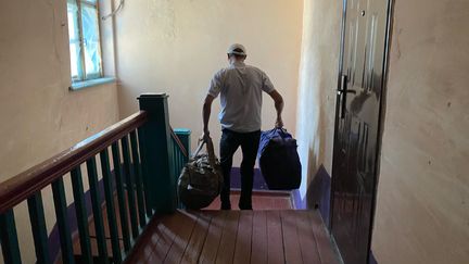 Un civil ukrainien quitte son domicile avec deux sacs, mardi 27 août à Ukrainsk, dans le sud-est de l'Ukraine. (BORIS LOUMAGNE / RADIO FRANCE)