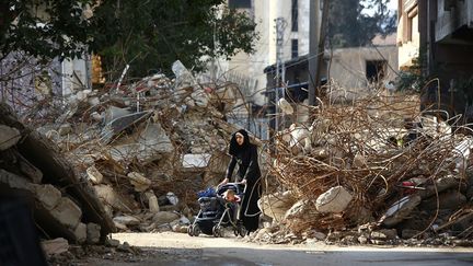 Une femme prom&egrave;ne son enfant parmi les d&eacute;combres &agrave; Douma (Syrie), le 13 d&eacute;cembre 2014. (ABD DOUMANY / AFP)