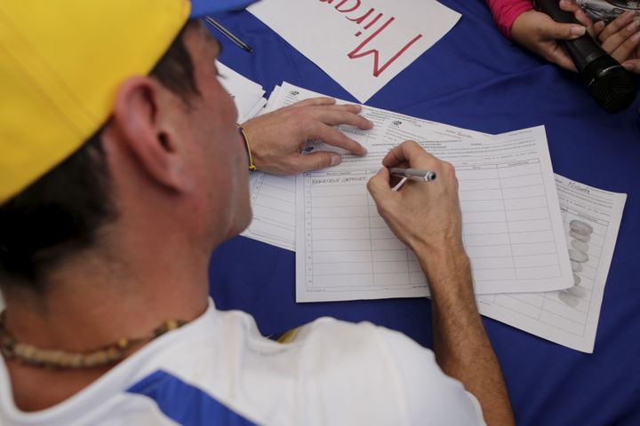 Au Venezuela, le chef de l'opposition et gouverneur de l'Etat du Miranda, Henrique Capriles, signe pour organiser un référendum contre le président, le 27 avril 2016 à Caracas (Venezuela). (MARCO BELLO / REUTERS)