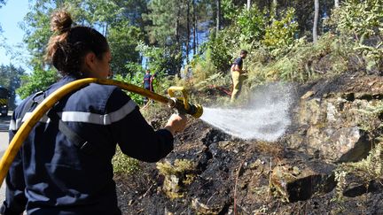 Des pompiers pulvérisent de l'eau pendant un incendie de forêt près de Besseges (Gard) , le 8 juillet 2022. (SYLVAIN THOMAS / AFP)