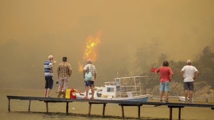 Des touristes observent l'incendie qui dévalent la colline alors qu'ils&nbsp;attendent d'être évacués de la zone de Mazi, à Bodrum,&nbsp;en Turquie, le dimanche 1er août 2021. (EMRE TAZEGUL/AP/SIPA / SIPA)