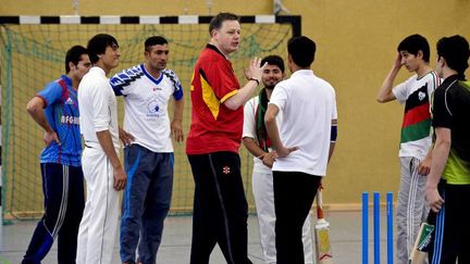 Des réfugiés afghans lors d'un entraînement de cricket  le 30 avril 2016, en compagnie du président de la fédération allemande. (AFP/ Sascha SCHÜRMANN )