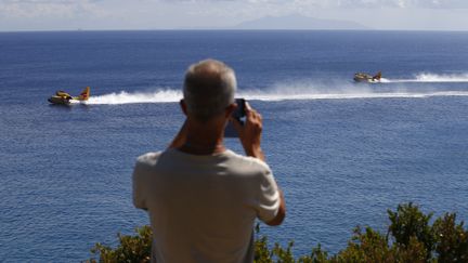 Un touriste prend des Canadairs en photo, près de Sisco, en Haute-Corse, le 12 août 2017.&nbsp; (PASCAL POCHARD-CASABIANCA / AFP)