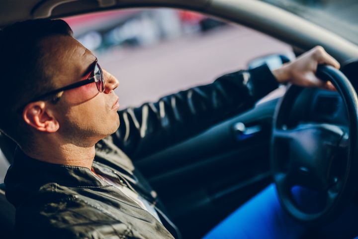 Un bel homme au volant d'une voiture... L'image du mâle dominant au volant&nbsp;pourrait être remplacée dans les publicités par des voitures remplies en copartage. Illustration (GETTY IMAGES)