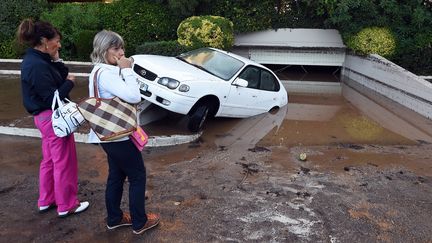 Des habitantes de&nbsp;Mandelieu-la-Napoule (Alpes-Maritimes) passent devant un parking souterrain rempli de boue apr&egrave;s les orages violents qui ont touch&eacute; le d&eacute;partement, le 4 octobre 2015. (BORIS HORVAT / AFP)