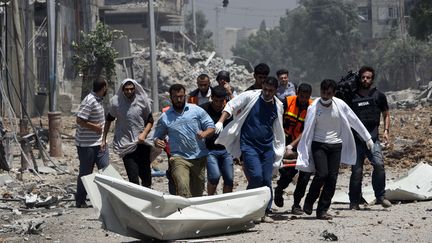 Les secours &eacute;vacuent un corps &agrave; Chajaya, en banlieue de Gaza, le 20 juillet 2014. (MAHMUD HAMS / AFP)