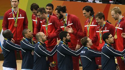 Les joueurs de l'équipe de France de handball saluent les joueurs danois, vainqueurs de la finale olympique, à Rio de Janeiro (Brésil), le 21 août 2016. (ROBERTO SCHMIDT / AFP)