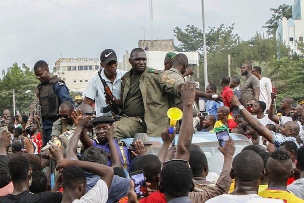 Une foule en liesse acclame des soldats et des policiers armés sur la place de l’Indépendance après le coup d’Etat contre le président Ibrahim Boubacar Keita. (AFP)