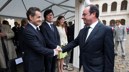 François Hollande et Nicolas Sarkozy se serrent la main lors de la cérémonie d'hommage&nbsp;aux harkis, le 25 septembre 2016, aux Invalides (Paris).&nbsp; (IAN LANGSDON / AFP)