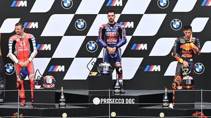 Miguel Oliveira sur la plus haute marche du podium, en compagnie de Jack Miller (2e) et Pol Espargaro (3e). (JOE KLAMAR / AFP)