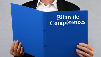 Un homme tient le dossier d'un bilan de compétences. (RICHARD VILLALON / MAXPPP)