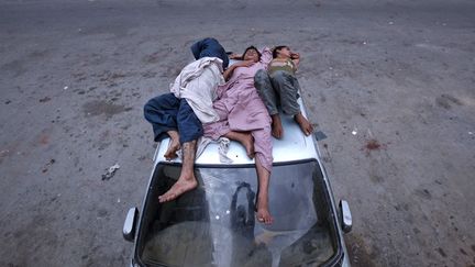 De jeunes sans-abris dorment sur le toit d'une voiture abandonn&eacute;e &agrave; Karachi (Pakistan), le 22 ao&ucirc;t 2012. (AKHTAR SOOMRO / REUTERS)