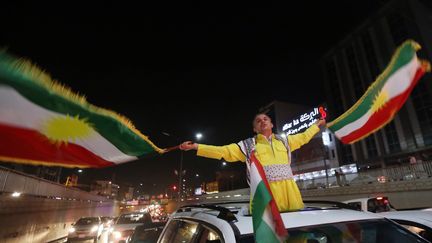 Un homme parade avec des drapeaux kurdes, le 27 septembre 2017, après l'annonce des résultats du référendum, à Erbil (Irak). (SAFIN HAMED / AFP)