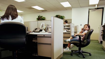 Une petite fille dans un bureau patiente en passant un coup de fil. (HOLLY HARRIS / STONE SUB)