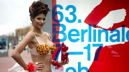 Le top model allemand Micaela Schaefer pose avec un ours en relief autocollant sur le "boulevard des Stars" devant l'affiche de la 63e Berlinale. 
 (ODD ANDERSEN / AFP)