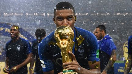 L'attaquant de l'équipe de France Kylian Mbappé embrasse le trophée de la Coupe du Monde, le 15 juillet 2018 à Moscou (Russie). (FRANCK FIFE / AFP)