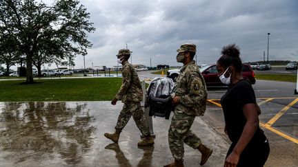 Des membres de la garde nationale assistent une femme lors de son évacuation à Lake Charles (Louisiane), le 8 octobre 2020. (CHANDAN KHANNA / AFP)