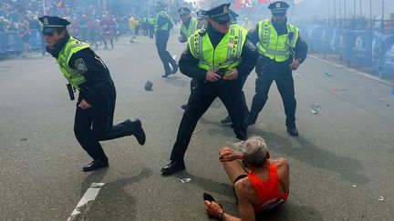 Des policiers entourent un septuagénaire après une attaque à l'explosif lors du marathon de Boston (Massachusetts), le 15 avril 2013. Trois personnes sont mortes et plus de 260 ont été blessées lors de cet attentat, commis par deux frères d'origines tchétchène. L'un d'entre eux a été tué par la police trois jours après l'attaque, tandis que l'autre a été arrêté et condamné à mort en mai 2015. (JOHN TLUMACKI / AP / SIPA)