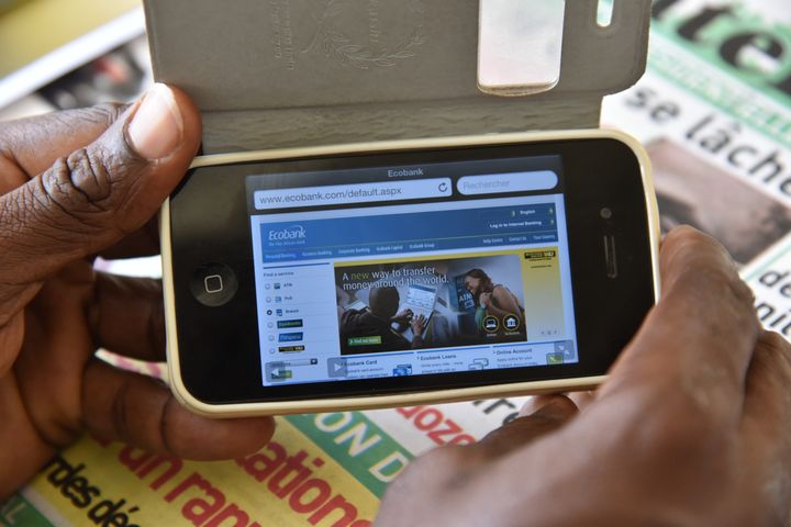 Un homme consulte son compte bancaire à partir de son smartphone le 24 avril 2015 à Abidjan (Côte d'Ivoire)&nbsp; (SIA KAMBOU / AFP)