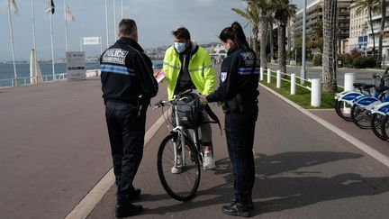 Des policiers contrôlent un cycliste sur la promenade des Anglais à Nice (Alpes-Maritimes), le 27 février 2021. (VALERY HACHE / AFP)