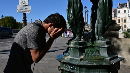 Un homme se rafraîchit dans une fontaine publique pendant une vague de chaleur, le 21 août 2023 à Paris. (MIGUEL MEDINA / AFP)