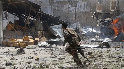 Un soldat somalien court pr&egrave;s du tribunal de Mogadiscio, dimanche 14 avril, pris d'assaut par des insurg&eacute;s islamistes pr&eacute;sum&eacute;s. (FEISAL OMAR / REUTERS)