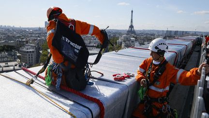 Les ouvriers mettent les dernières touches à l'Arc de Triomphe empaqueté de Christo,&nbsp;en déployant&nbsp;les derniers mètres de cordages rouges (3 000 mètres de cordes au total) qui entourent le monument habillé de tissu recyclé argent bleuté, le 16 septembre 2021. (THOMAS SAMSON / AFP)