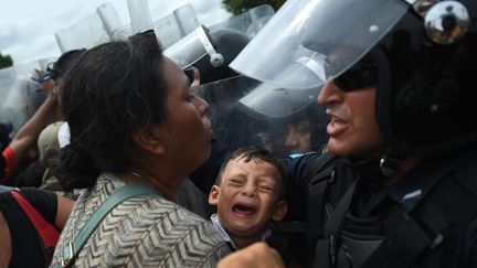 Des policiers empêchent&nbsp;des réfugiés honduriens de pénétrer sur le territoire mexicain, le 19 octobre 2018 à Ciudad Hidalgo (Mexique). (PEDRO PARDO / AFP)