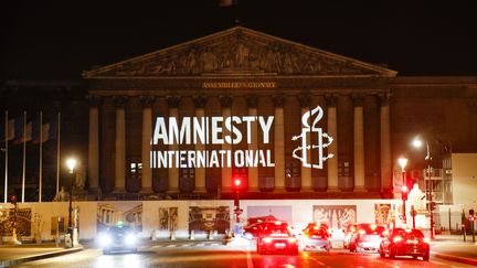 Le logo&nbsp;de l'ONG Amnesty International projeté sur le&nbsp;Palais Bourbon à Paris, le 18 juin 2018.&nbsp; (GEOFFROY VAN DER HASSELT / AFP)