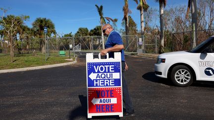 Un homme installe un panneau d'indication pour diriger les électeurs vers les bureaux de vote à Fort Myers (Floride), le 24 octobre 2022. (JOE RAEDLE / GETTY IMAGES NORTH AMERICA)