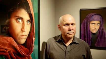 Le photographe américain Steve McCurry pose à côté des clichés qu'il a pris de Sharbat Gula, lors de l'exposition «Overwhelmed by Life» à Hambourg, le 27 juin 2013. (ULRICH PERREY / DPA / AFP)