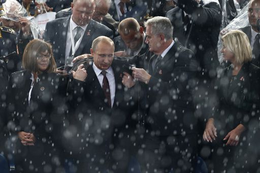 Le président serbe, Tomislav Nikolic, aide son homologue russe, Vladimir Poutine, à mettre son manteau le 16 octobre 2014 lors d'un défilé militaire à Belgrade marquant le 70e anniversaire de la libération de la ville par l'armée soviétique à la fin de la Seconde guerre mondiale. (REUTERS - Marko Djurica)