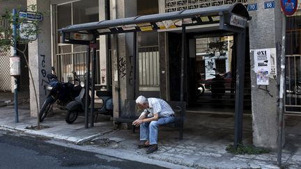 Un homme attend &agrave; un arr&ecirc;t de bus, le 12 juillet 2015 &agrave; Ath&egrave;nes (Gr&egrave;ce). (ANGELOS TZORTZINIS / AFP)