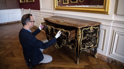 Le directeur du Musée National du château de Versailles, Laurent Salome, inspecte la magnifique commode du XVIIIe siècle que vient d'acquérir le Musée pour 4 millions d'euros. Le meuble avait disparu pendant la Révolution française.&nbsp; (CHRISTOPHE ARCHAMBAULT / AFP)