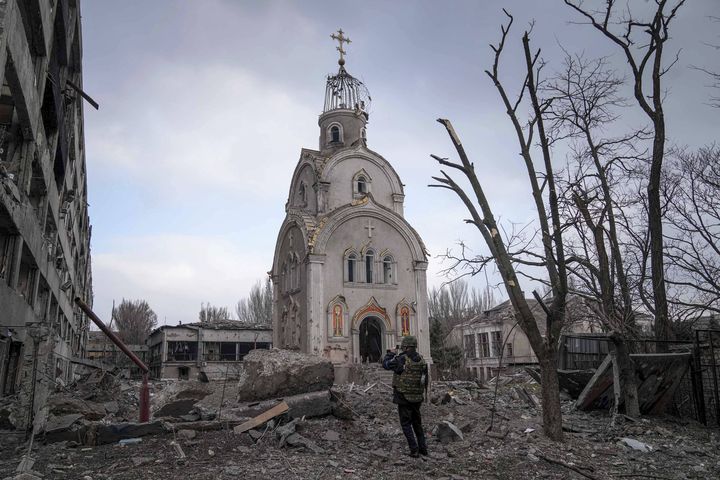 Un militaire ukrainien prend une photo d'une église en partie debout dans un quartier résidentiel détruit de Marioupol en Ukraine, le 10 mars 2022. (EVGENIY MALOLETKA/AP/SIPA / SIPA)