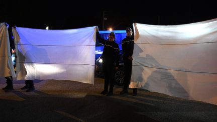 Des gendarmes tiennent des draps afin de cacher la reconstitution de la nuit du meurtre de Maëlys, le 24 septembre 2018, à Domessin (Savoie). (JEAN-PIERRE CLATOT / AFP)