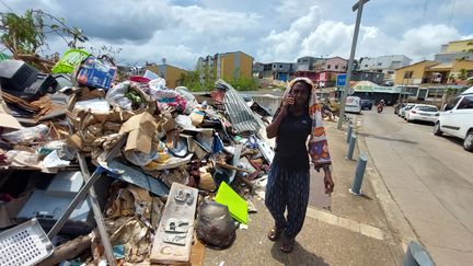 Une femme marche à côté d'un monticule de déchets sur un trottoir de Mamoudzou, le 27 décembre 2024. (AGATHE MAHUET / FRANCE INFO / RADIO FRANCE)