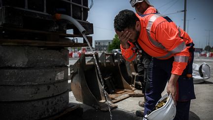 Un travailleur s'hydrate le visage sur un chantier de travaux publics à Mérignac (Gironde) par une journée de forte chaleur, le 14 juin 2022. (PHILIPPE LOPEZ / AFP)