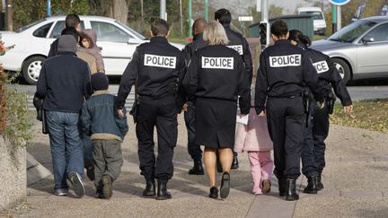 Des membres de la police de l'air et des frontières escortent une famille à la sortie du tribunal de Cergy, vers l'aéroport de Roissy, lors d'une procédure de reconduite&nbsp;à la frontière, le 10 novembre 2006. (JACK GUEZ / AFP)