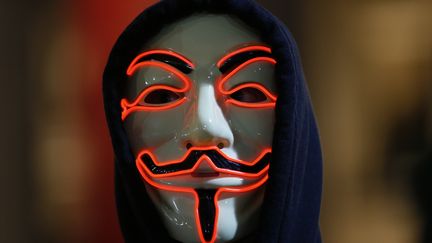 Un membre d'Anonymous à Londres porte un masque aux traits rouges. La&nbsp;plupart des manifestants portaient un masque pour ne pas être reconnus, mais certains ayant rejoint la marche en route, ont marché le visage découvert. (PETER NICHOLLS / REUTERS)