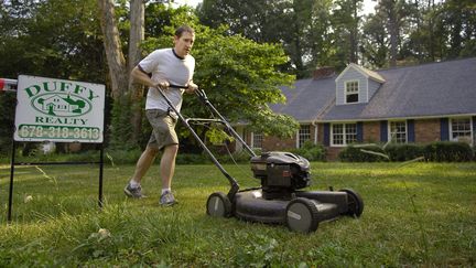 Un homme passe la tondeuse sur sa pelouse devant sa maison à&nbsp; Atlanta (États-Unis). (MAXPPP)