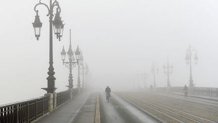 Un cycliste affronte le brouillard sur le Pont de pierre de Bordeaux (Gironde), le 6 décembre 2017. (NICOLAS TUCAT / AFP)