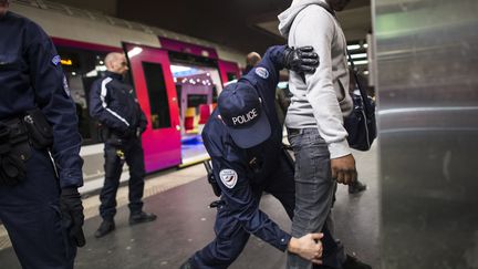 Un policier contr&ocirc;le un individu &agrave; la gare du Nord &agrave; Paris, le 30 novembre 2012. (FRED DUFOUR / AFP)