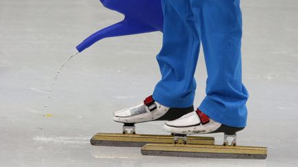 Un membre de l'organisation des JO verse de l'eau sur la piste du patinage de vitesse pour corriger les d&eacute;fauts de la glace, le 10 f&eacute;vrier 2014. (DAVID GRAY / REUTERS)