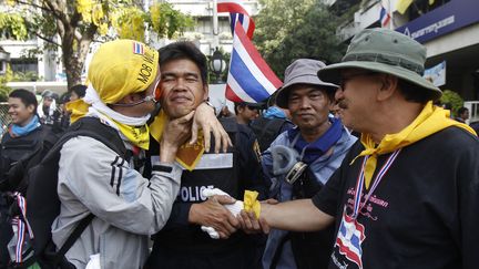 Des manifestants hostiles au gouvernement fraternisant avec un policier, &agrave; Bangkok (Tha&iuml;lande), le 3 d&eacute;cembre 2013. (CHAIWAT SUBPRASOM / REUTERS)