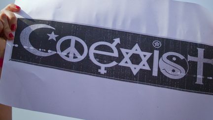 Une manifestante tient une affiche avec les symboles des différentes religions à Paris, en mars 2012.&nbsp; (JOEL SAGET / AFP)