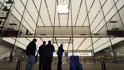 Des passants devant une boutique Apple qui s'appr&ecirc;te &agrave; ouvrir, dans la ville chinoise de Hangzou, le 22 janvier 2015. (WANG QIAN / AFP)