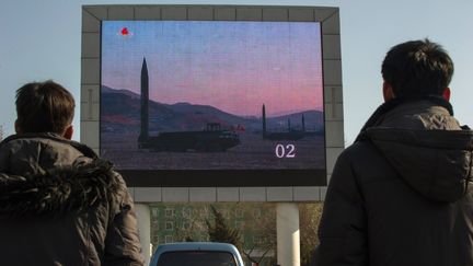 Des Nord-Coréens regardent le lancement d'un missile balistique sur un écran installé devant la gare centrale de Pyongyang, le 7 mars 2017. (KIM WON-JIN / AFP)